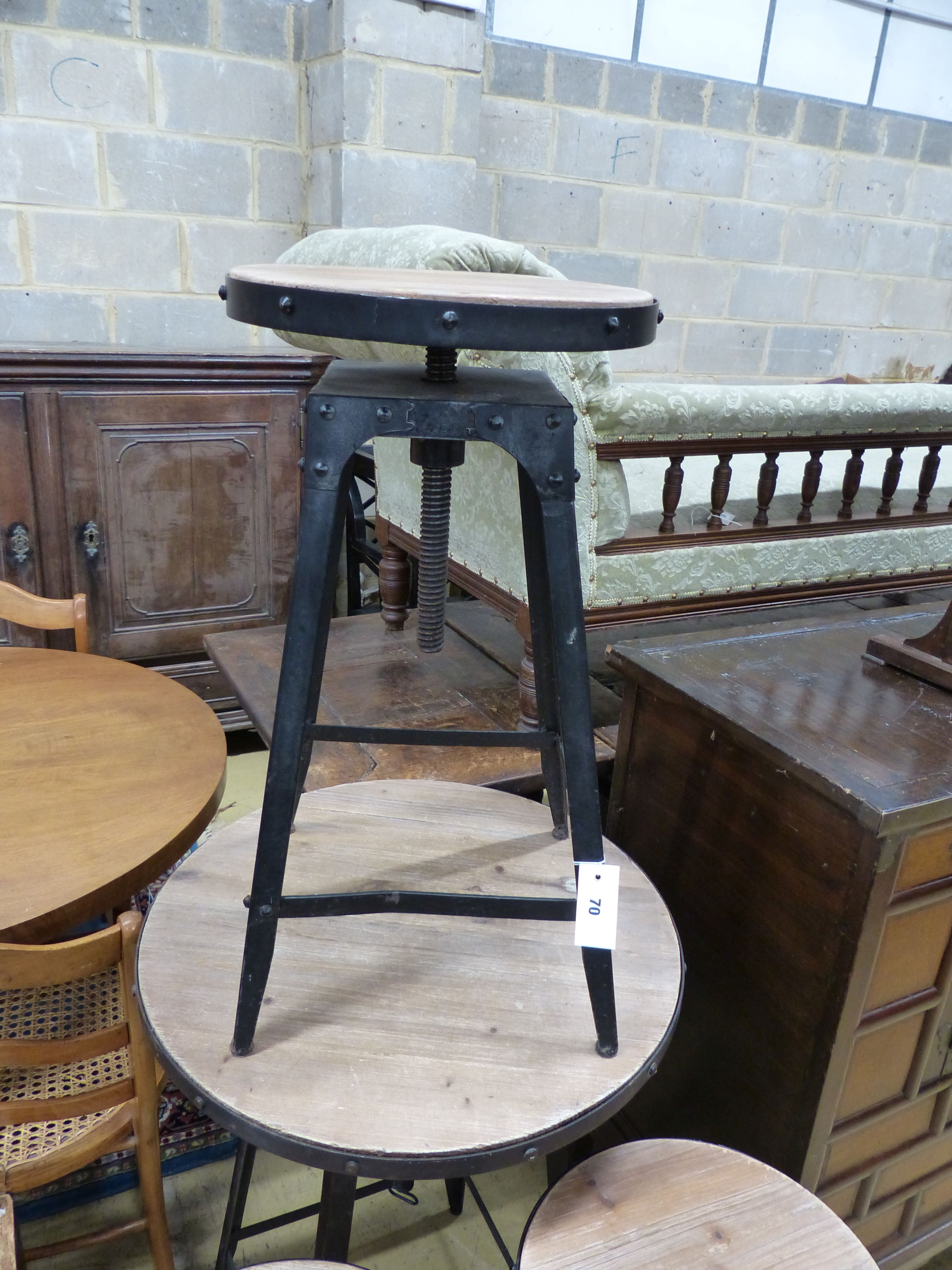 An adjustable wrought iron pub table and three matching telescopic stools